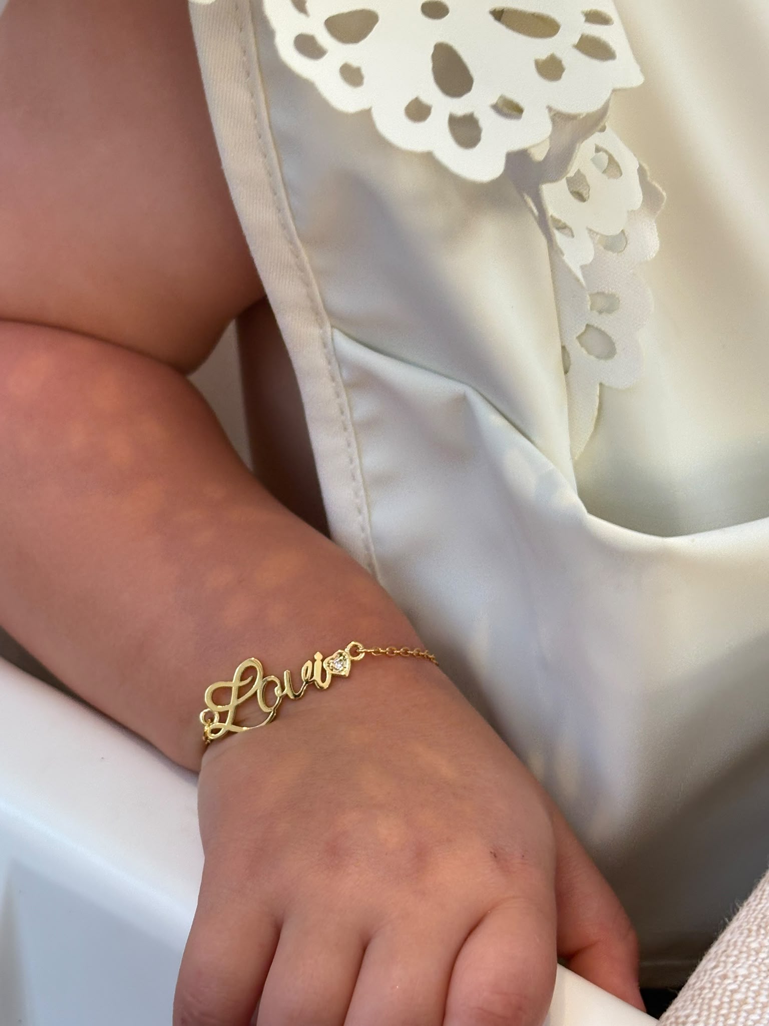 Lovi Baby bracelet met naam en hartje, gedragen om een kinderpols